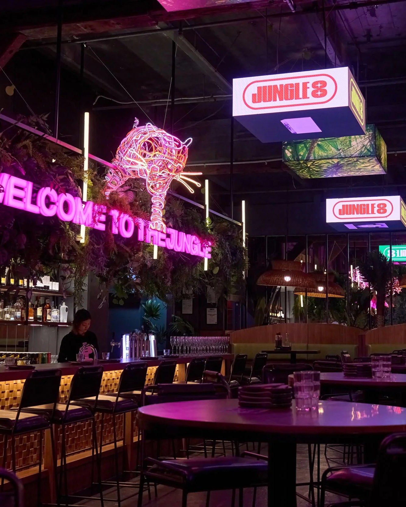 Jungle 8 dining room — neon tiger sign, pink lamps, leafy plants
